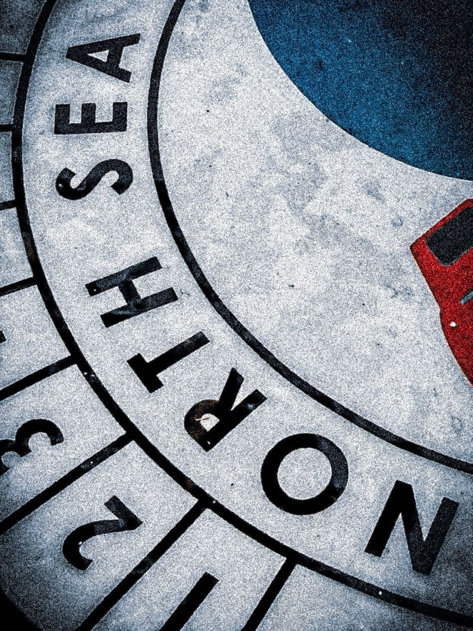 a close-up of a compass-style pavement plaque reading "North Sea" in bold lettering