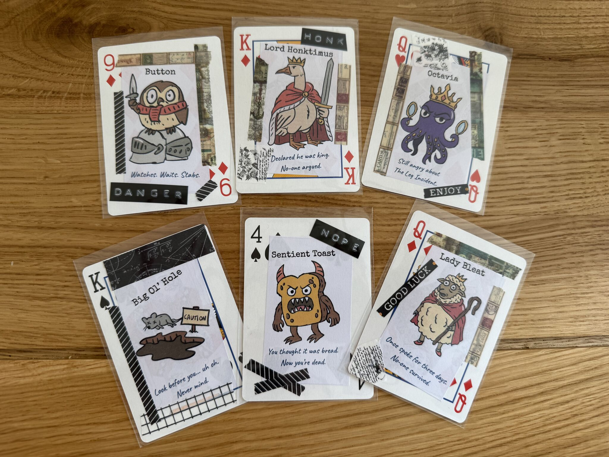 six hand-drawn poker cards spread on a wooden table showing characters including Octavia the octopus, Sentient Toast, and Lady Bleat the sheep
